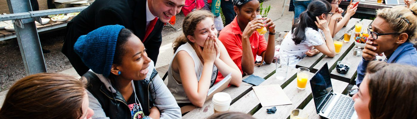 Young people talking while seated at a picnic bench.